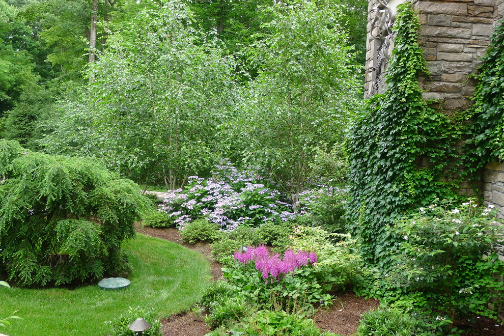 Exemple d'un jardin sur cour chic de taille moyenne avec un mur de soutènement et des pavés en pierre naturelle.