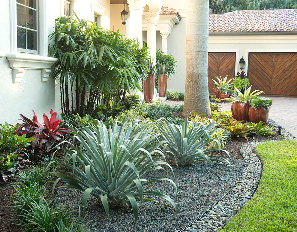 Foto de jardín tropical grande en patio delantero con exposición parcial al sol y adoquines de ladrillo