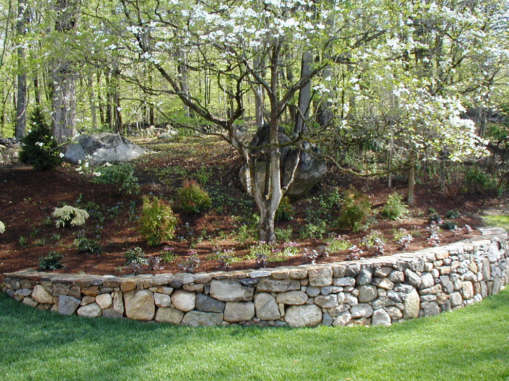 Aménagement d'un grand jardin arrière campagne l'été avec une exposition ombragée et des pavés en pierre naturelle.