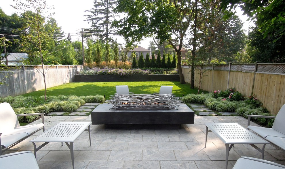 Modelo de jardín actual en patio trasero con brasero, exposición parcial al sol y adoquines de piedra natural