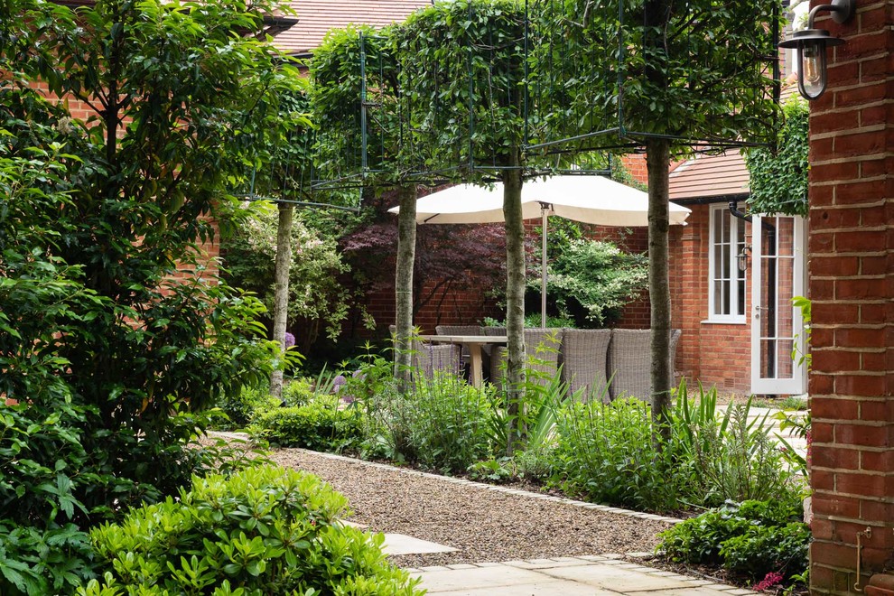 На фото: весенний регулярный сад среднего размера на заднем дворе в классическом стиле с местом для костра, полуденной тенью и покрытием из каменной брусчатки