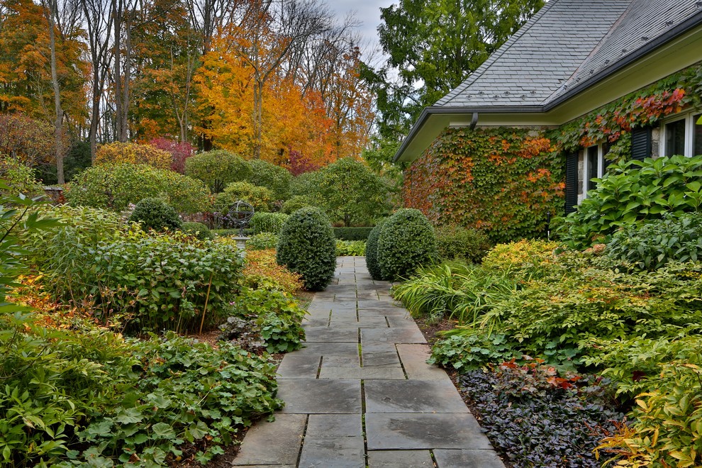 Imagen de camino de jardín clásico de tamaño medio en otoño en patio delantero con adoquines de piedra natural, jardín francés y exposición parcial al sol