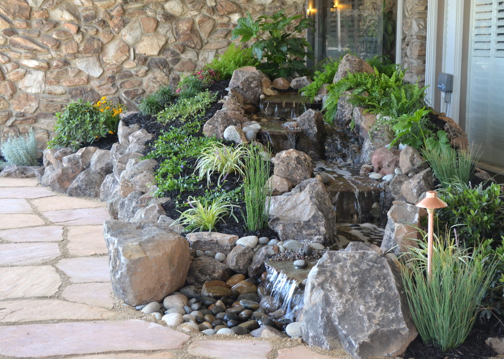 Foto de jardín tropical de tamaño medio con adoquines de piedra natural y cascada