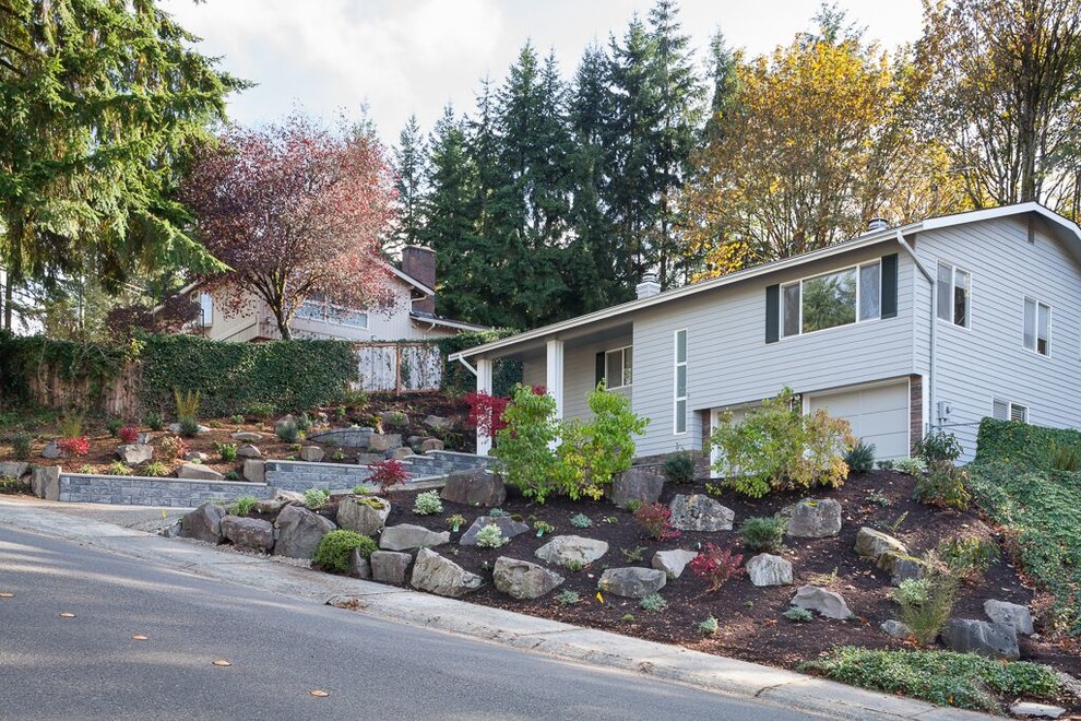 Photo of a large classic front formal partial sun garden in Seattle with a retaining wall and mulch.