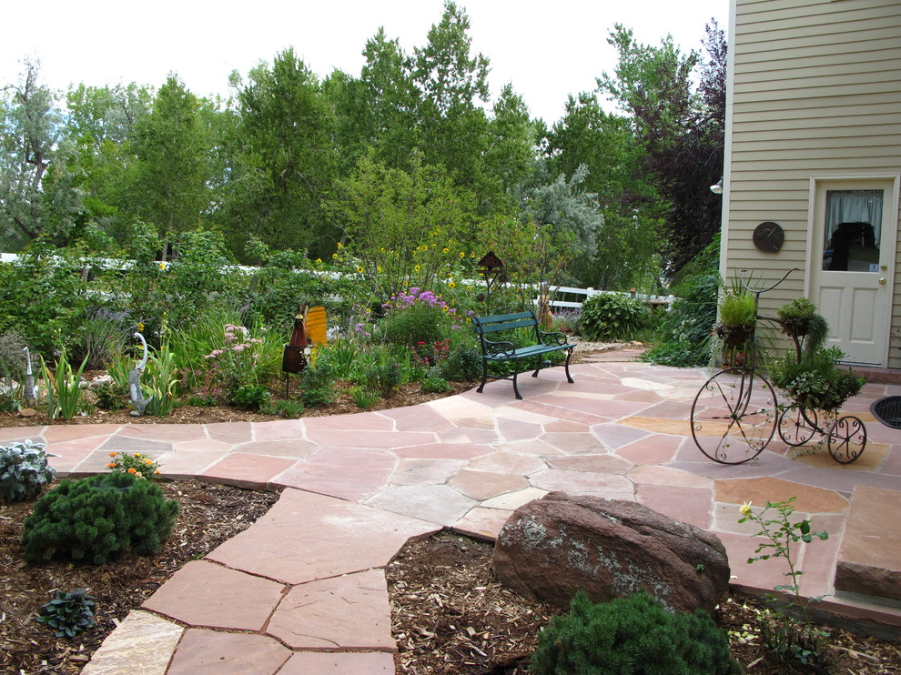 This is an example of a mid-sized traditional partial sun backyard stone landscaping in Denver for summer.