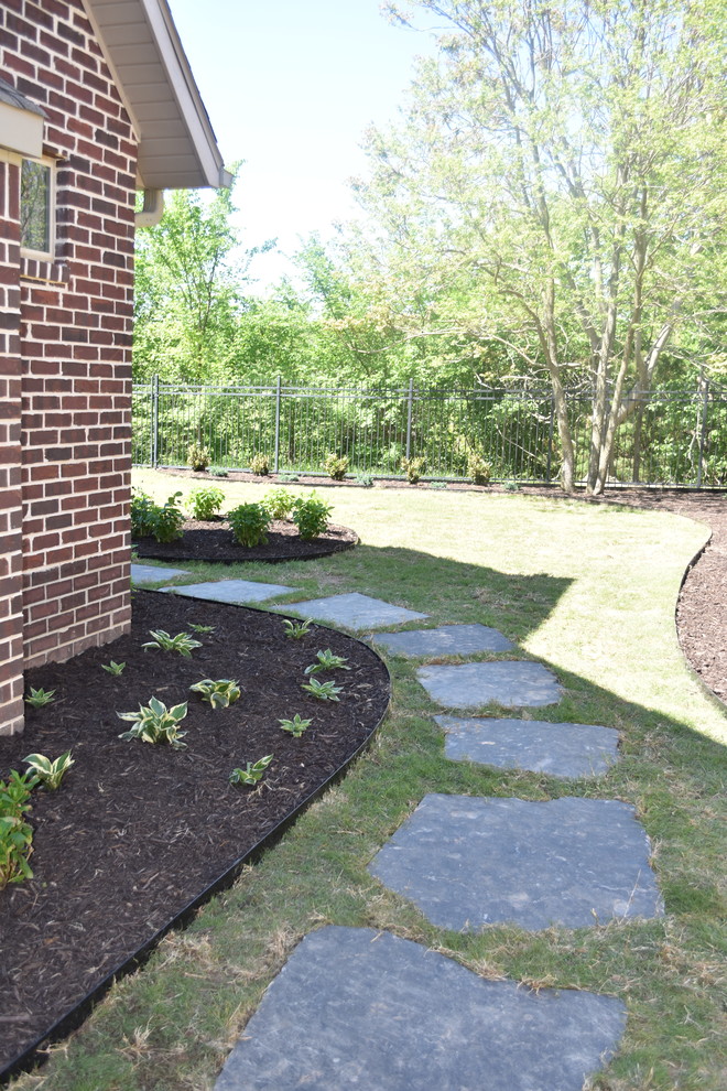 Large classic back formal partial sun garden in Other with a garden path and natural stone paving.