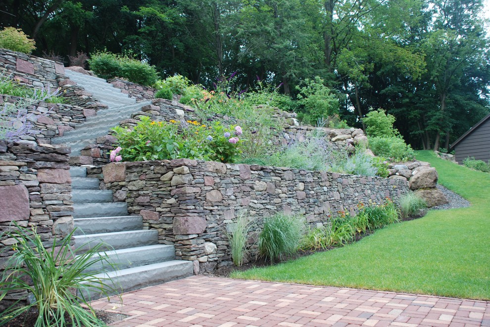Inspiration for a medium sized classic sloped formal garden in New York with a garden path and natural stone paving.