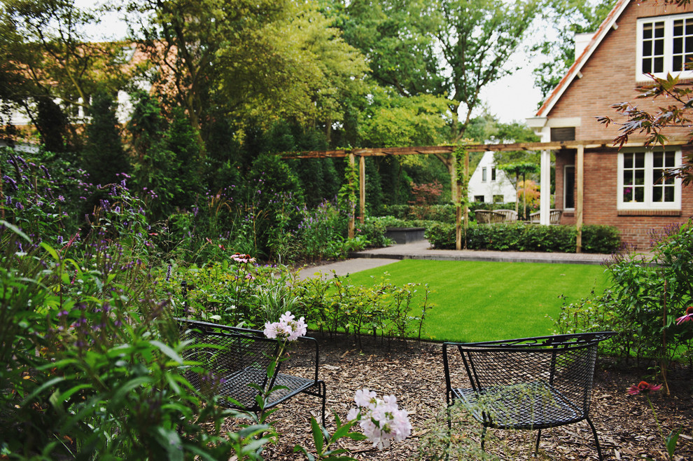 Diseño de jardín clásico grande en patio trasero con mantillo
