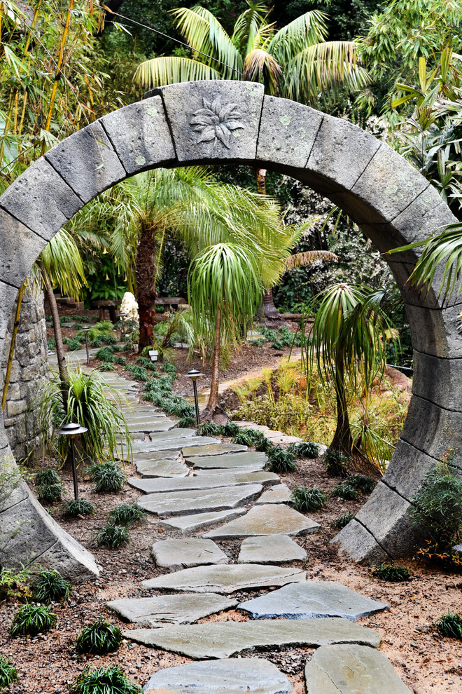 Foto di un grande giardino tropicale esposto a mezz'ombra dietro casa in estate con un ingresso o sentiero e pavimentazioni in pietra naturale