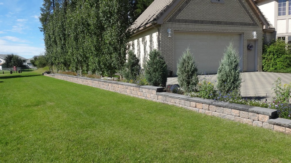 Aménagement d'un jardin latéral de taille moyenne avec un mur de soutènement, une exposition ensoleillée et des pavés en béton.
