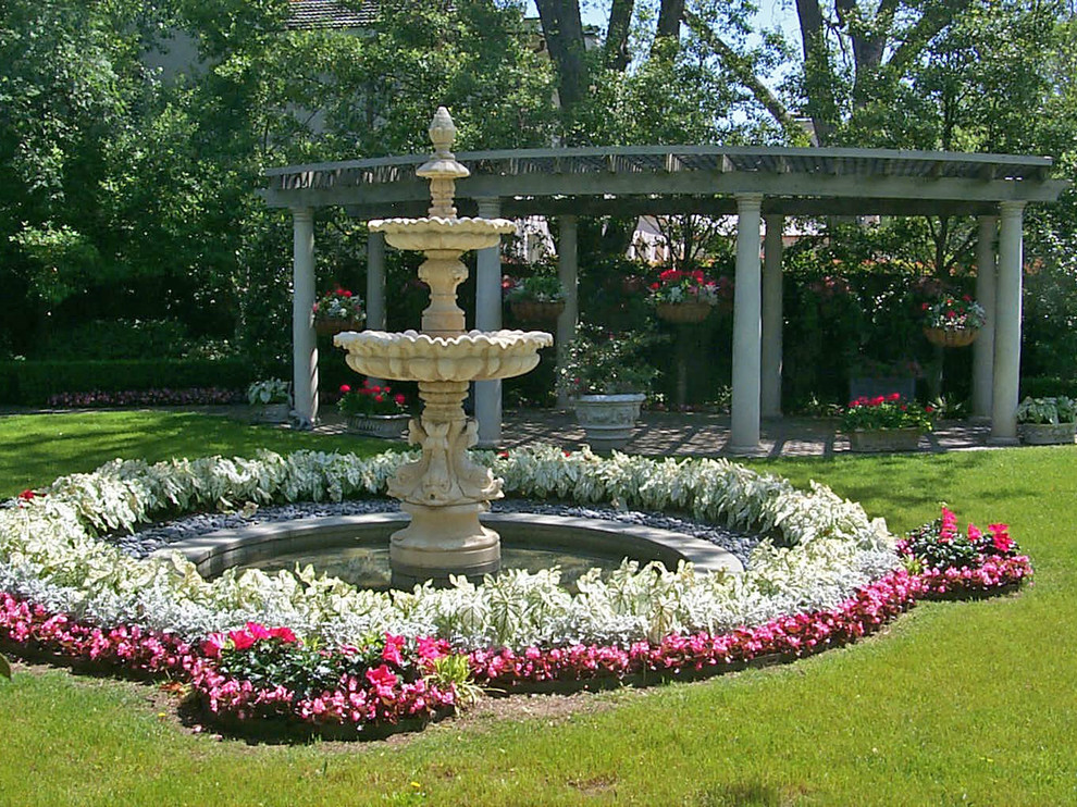 Foto på en vintage trädgård i delvis sol, med en fontän och naturstensplattor