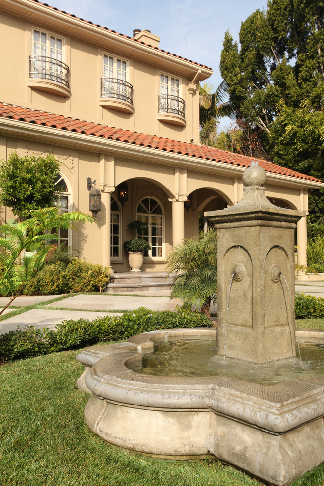 Diseño de jardín mediterráneo grande en patio delantero con fuente, exposición total al sol y adoquines de piedra natural