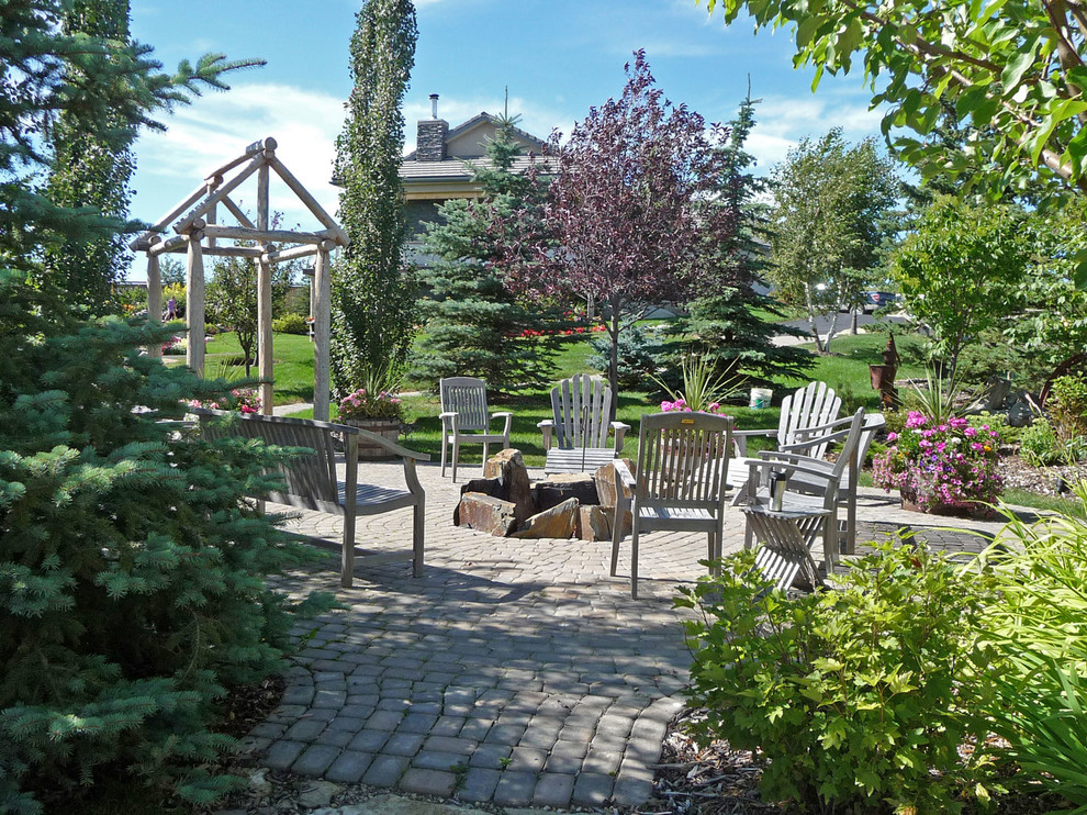 Aménagement d'un jardin arrière classique l'été avec un foyer extérieur, une exposition ensoleillée et des pavés en béton.