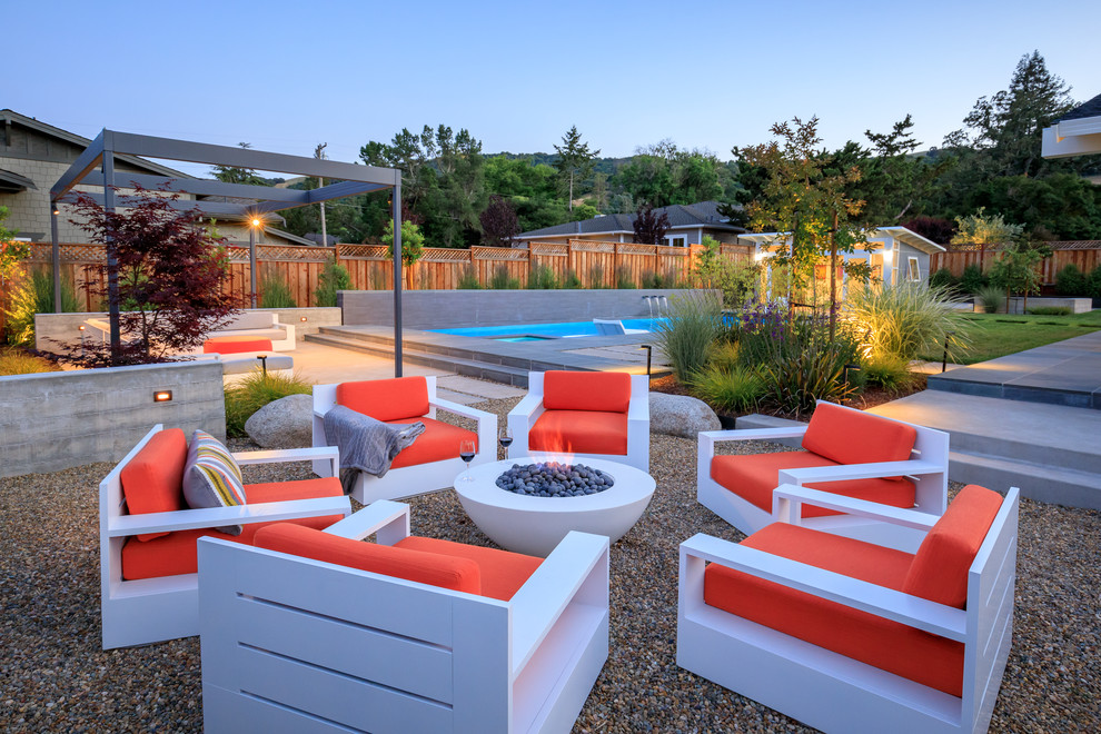 Идея дизайна: солнечный, летний засухоустойчивый сад на заднем дворе в современном стиле с местом для костра, хорошей освещенностью и мощением тротуарной плиткой