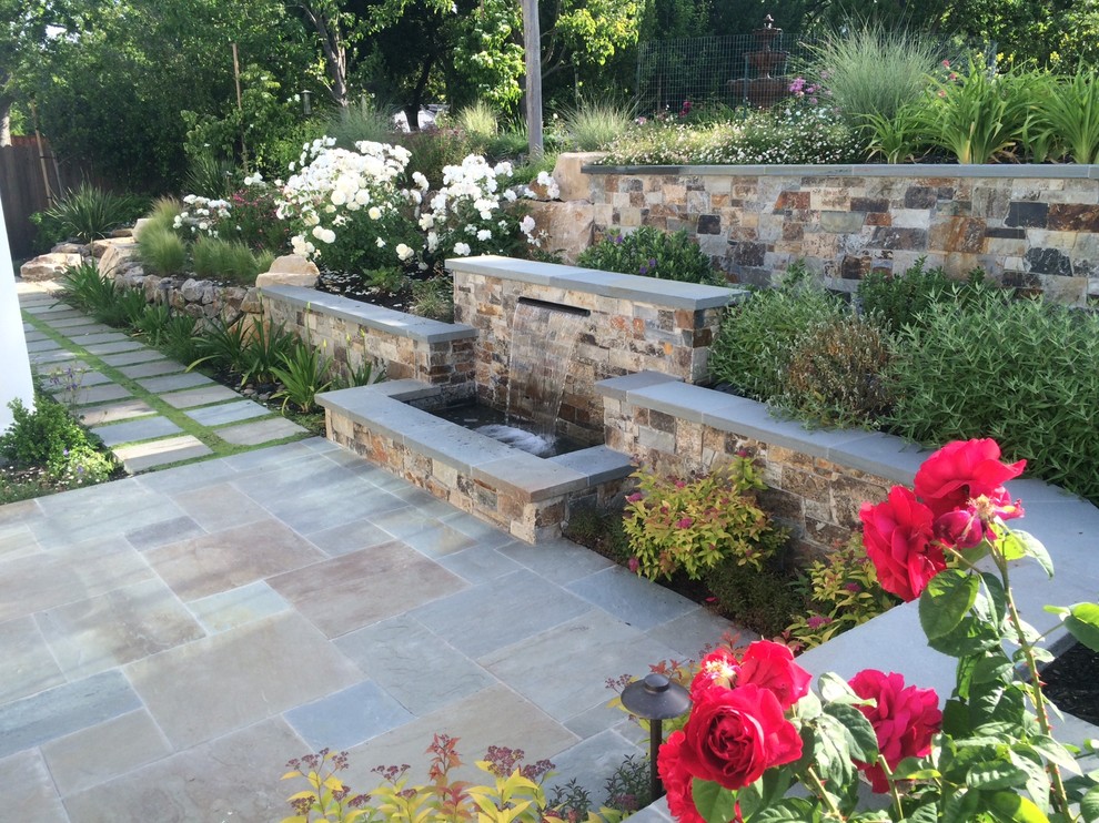Esempio di un grande giardino classico esposto in pieno sole dietro casa in estate con un muro di contenimento e pavimentazioni in pietra naturale