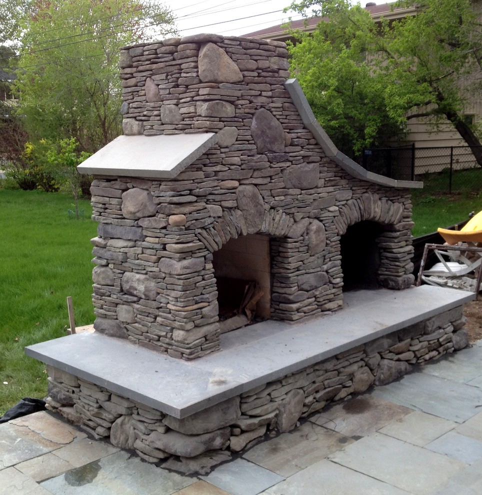 Foto di un grande patio o portico american style dietro casa con un focolare e pavimentazioni in pietra naturale