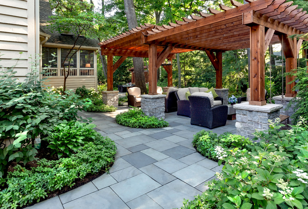 Diseño de jardín clásico grande en verano en patio trasero con exposición reducida al sol, adoquines de piedra natural y pérgola