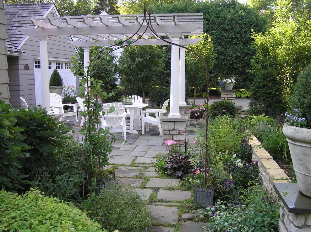 Diseño de jardín clásico en patio trasero con adoquines de piedra natural y pérgola