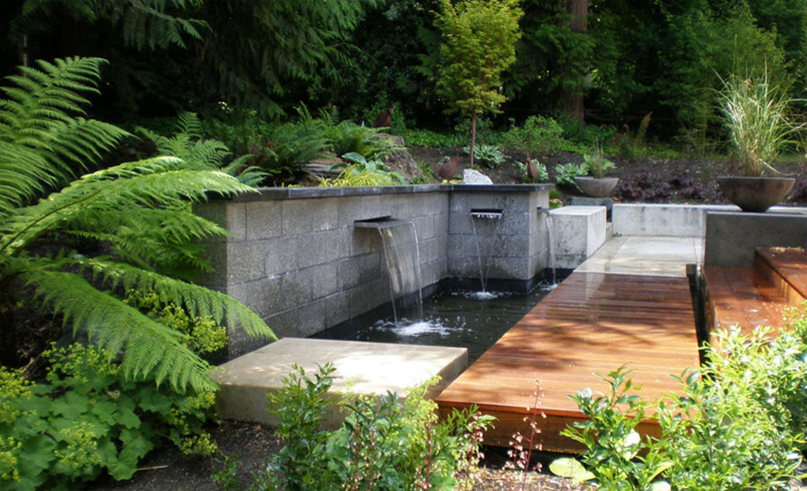Foto på en stor funkis trädgård i delvis sol, med en fontän och marksten i betong