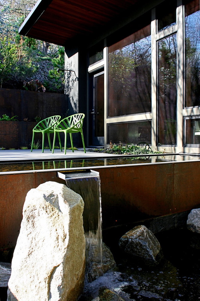 This is an example of a modern garden in Seattle with a water feature and decking.