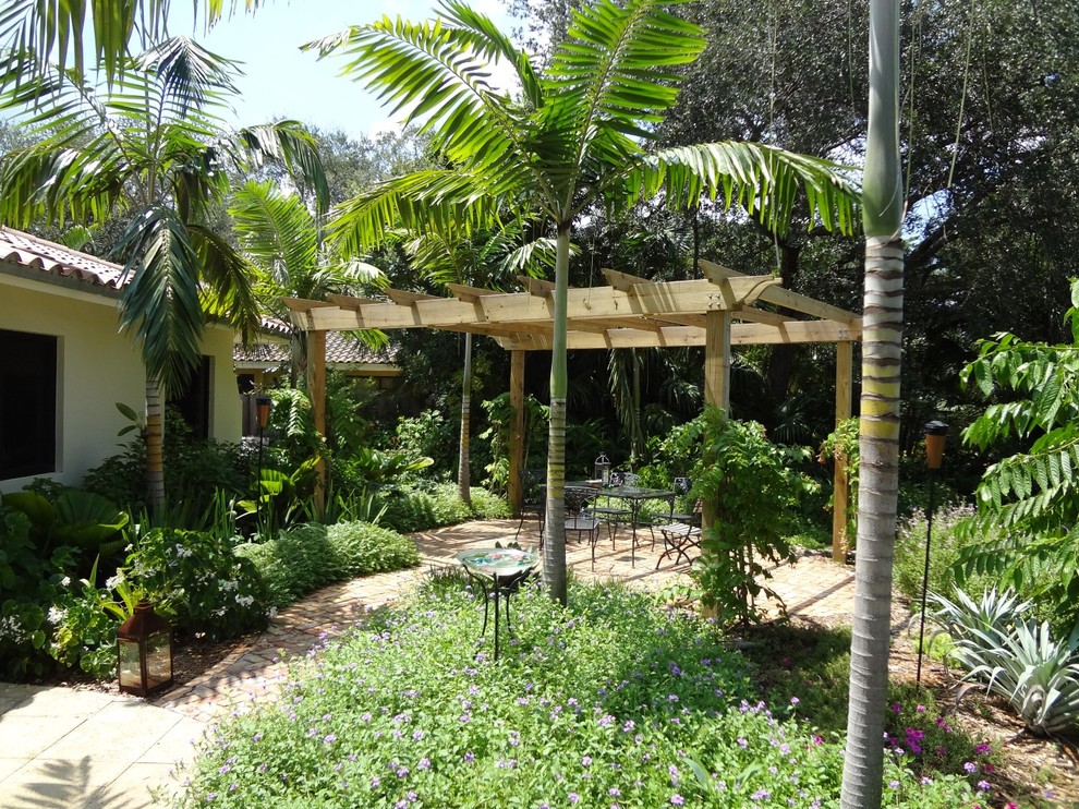 Foto de jardín tropical de tamaño medio en verano en patio trasero con exposición total al sol y adoquines de piedra natural