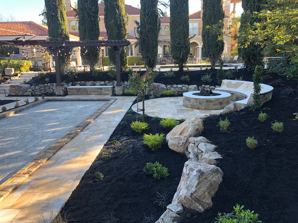 Ejemplo de jardín de secano mediterráneo grande en patio trasero con brasero y adoquines de piedra natural
