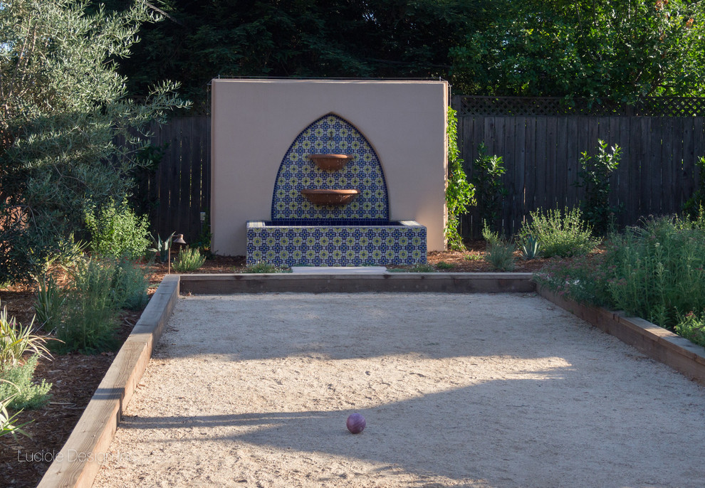 Idéer för att renovera en mellanstor medelhavsstil bakgård i full sol, med en fontän och granitkomposit