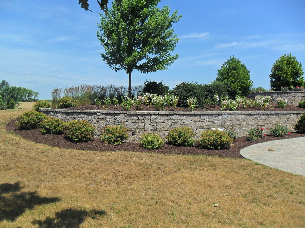 Photo of a medium sized traditional back full sun garden in Milwaukee with a retaining wall and natural stone paving.