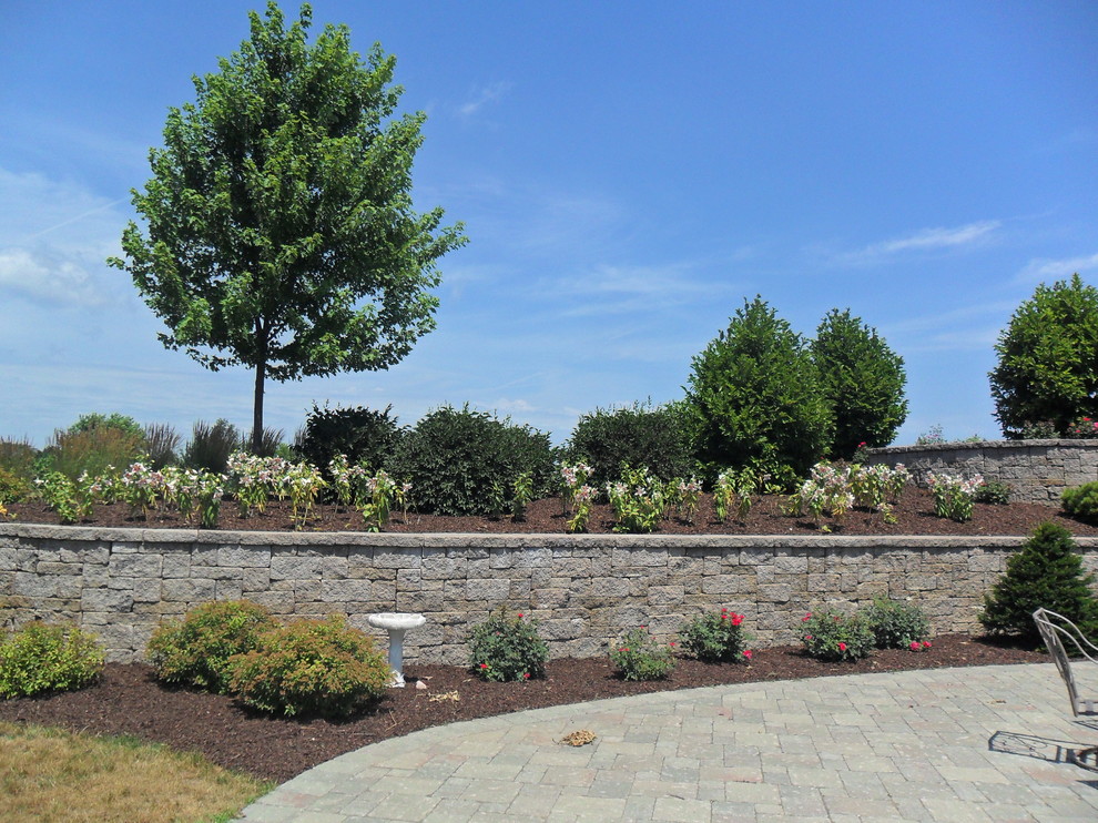 Foto di un giardino classico esposto in pieno sole di medie dimensioni e dietro casa con un muro di contenimento e pavimentazioni in pietra naturale
