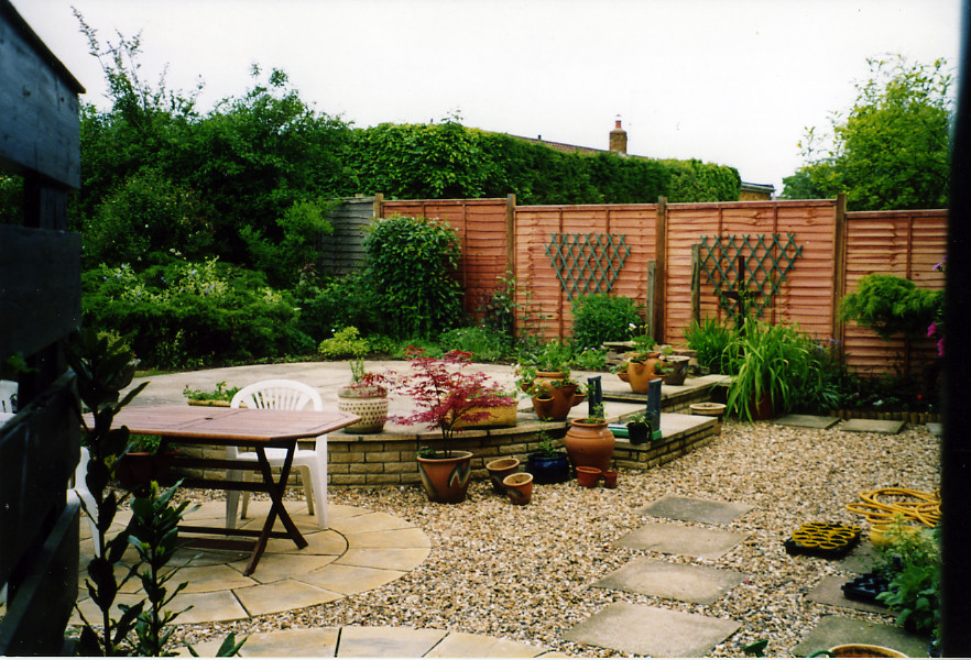 Immagine di un piccolo giardino mediterraneo esposto in pieno sole dietro casa in estate con un giardino in vaso e pavimentazioni in cemento