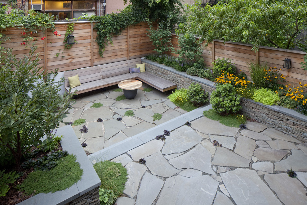 Foto de jardín contemporáneo de tamaño medio en verano en patio trasero con muro de contención, exposición total al sol y adoquines de piedra natural