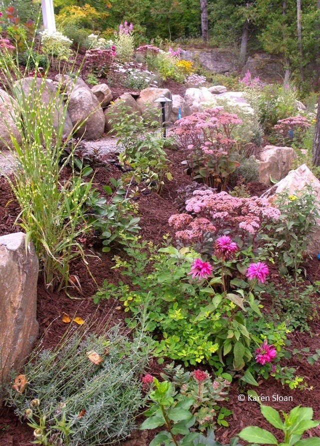 This is an example of a large coastal drought-tolerant and full sun hillside gravel retaining wall landscape in Toronto.