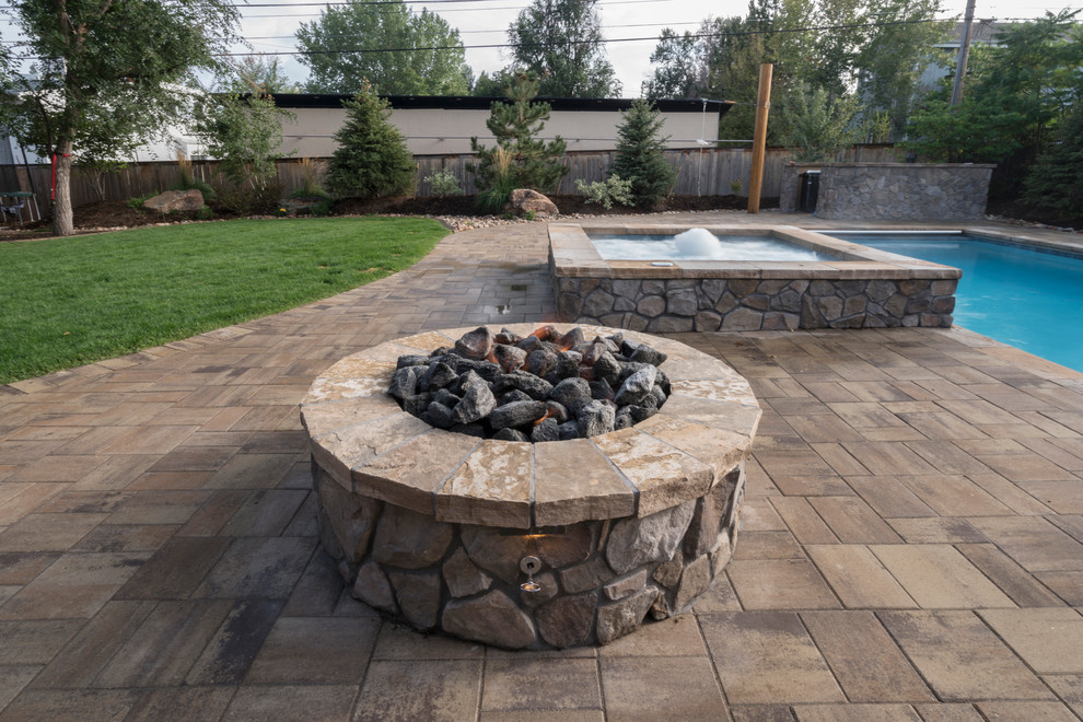 This is an example of a traditional back full sun garden for summer in Denver with a fire feature and concrete paving.