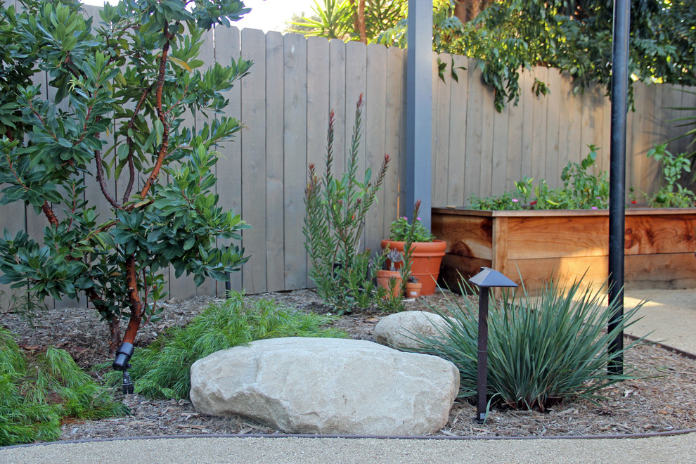 Mittelgroßer, Halbschattiger Rustikaler Garten hinter dem Haus, im Frühling mit Blumenbeet, Granitsplitt und Holzzaun in San Diego