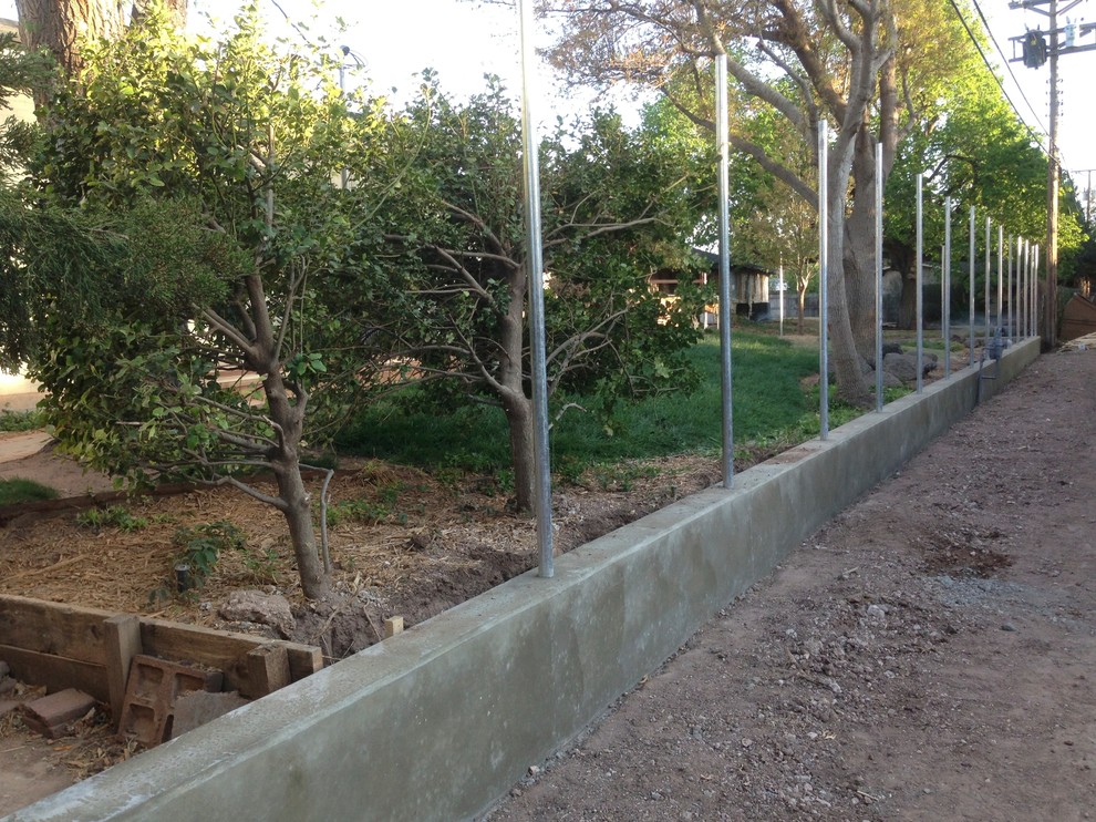 Immagine di un grande giardino american style dietro casa con un muro di contenimento e pavimentazioni in cemento