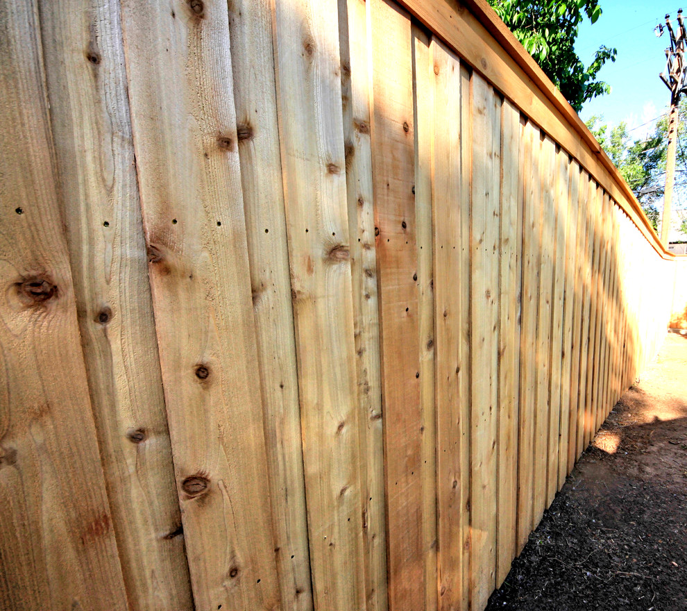 Aménagement d'un grand jardin arrière craftsman avec un mur de soutènement et des pavés en béton.