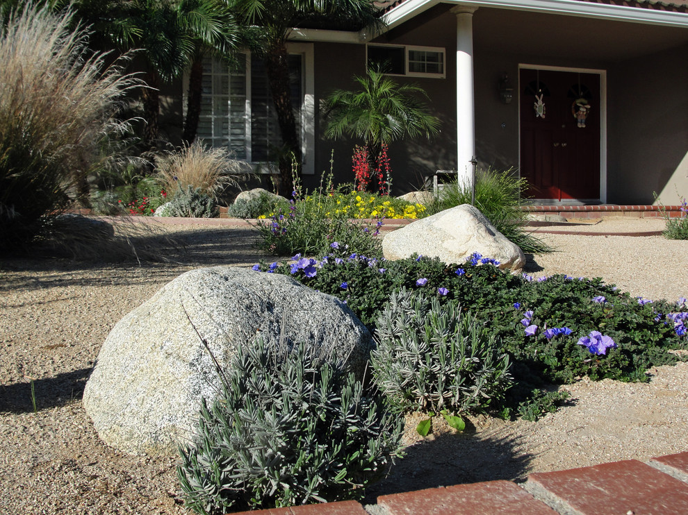 Diseño de camino de jardín de estilo americano de tamaño medio en primavera en patio delantero con jardín francés, exposición total al sol y gravilla