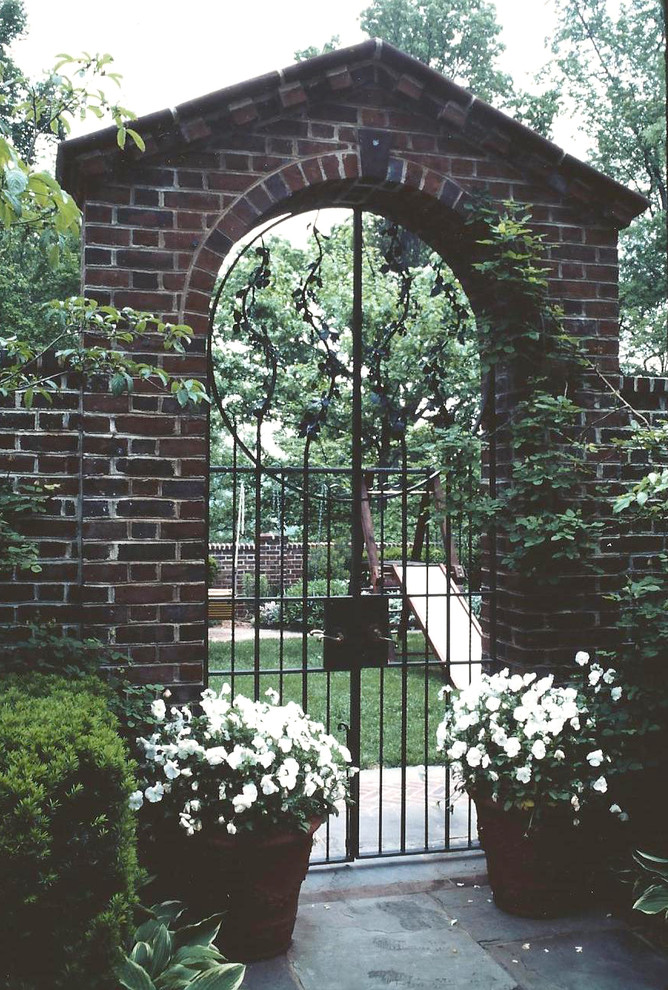 Идея дизайна: огромный солнечный, весенний регулярный сад на внутреннем дворе в классическом стиле с хорошей освещенностью, покрытием из каменной брусчатки и садовой дорожкой или калиткой
