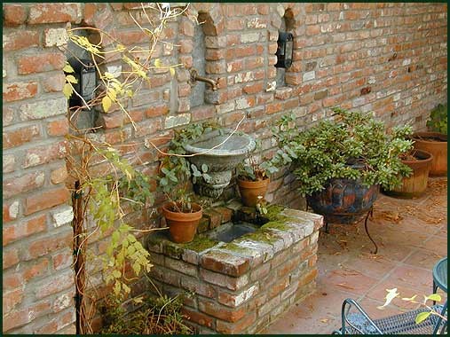 Esempio di un giardino mediterraneo in ombra in cortile in primavera con un giardino in vaso e pavimentazioni in mattoni