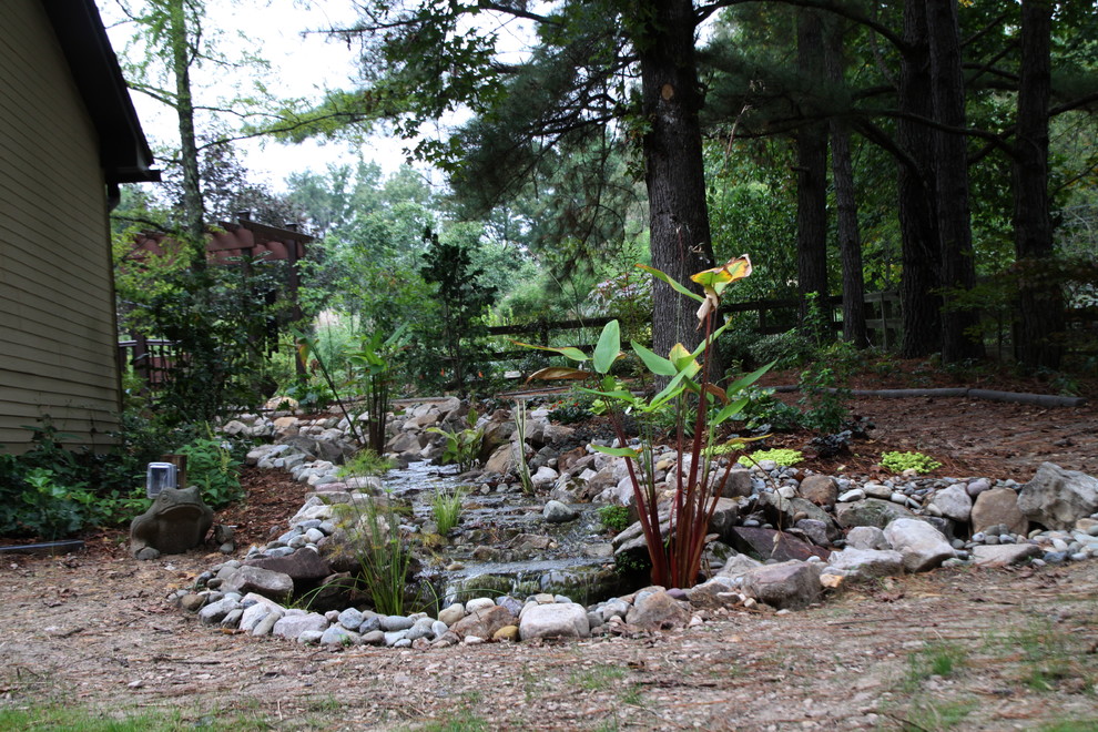 Imagen de jardín exótico pequeño en patio trasero con fuente, exposición reducida al sol y entablado