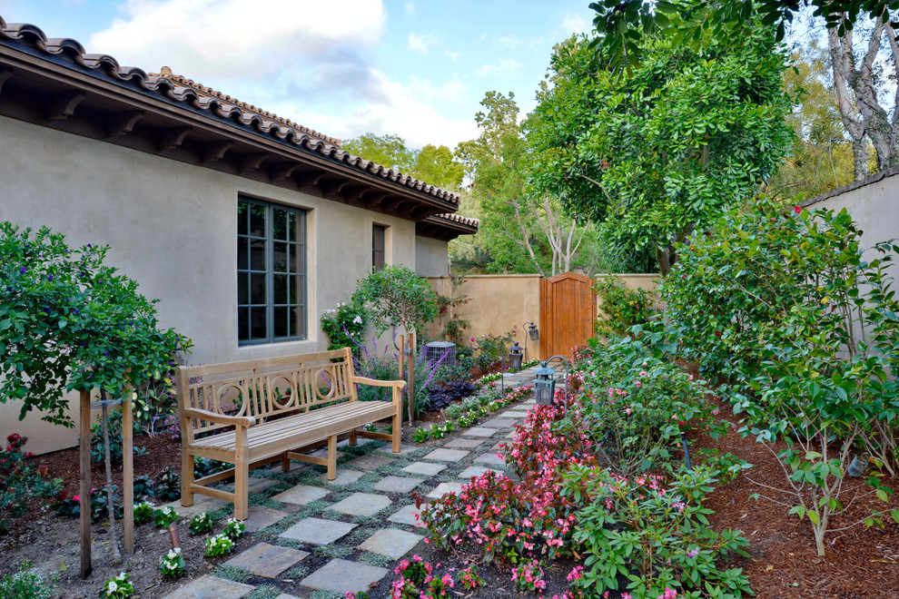 Ejemplo de camino de jardín de estilo americano de tamaño medio en primavera en patio lateral con jardín francés, exposición parcial al sol y adoquines de piedra natural