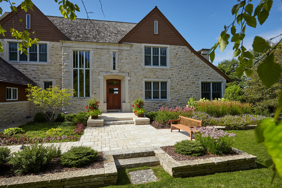 Ejemplo de jardín actual de tamaño medio en patio delantero con muro de contención y adoquines de piedra natural