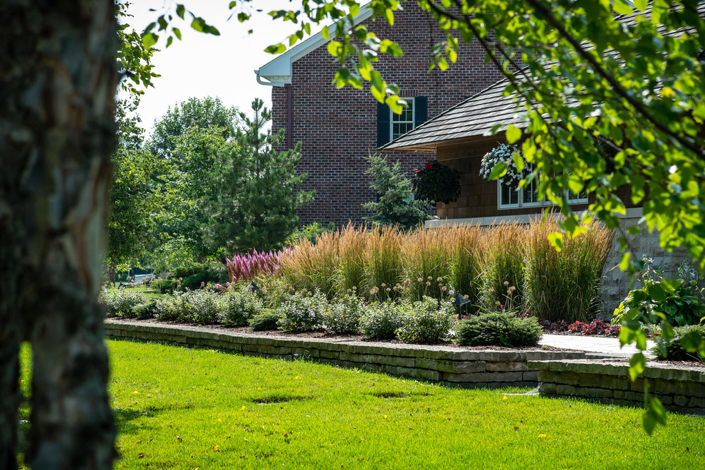 Ejemplo de jardín contemporáneo de tamaño medio en patio delantero con muro de contención y adoquines de piedra natural