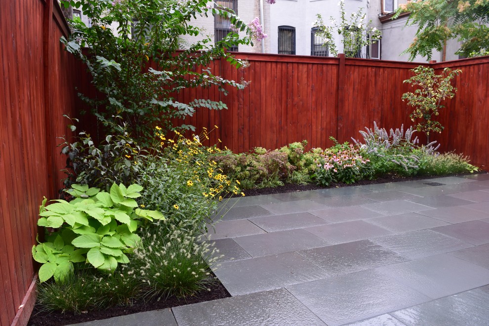 Imagen de jardín moderno pequeño en verano en patio trasero con jardín francés, exposición total al sol y adoquines de piedra natural
