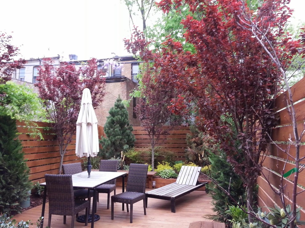 This is an example of a medium sized modern front formal full sun garden for spring in New York with decking.