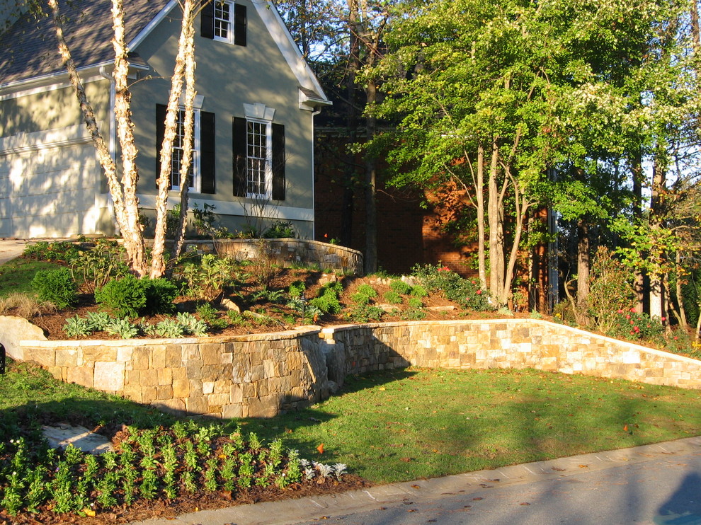 Cette image montre un grand jardin à la française latéral traditionnel avec un mur de soutènement, une exposition partiellement ombragée et des pavés en pierre naturelle.
