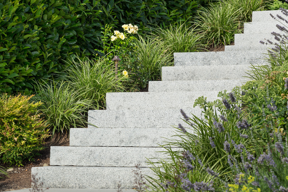Ispirazione per un grande giardino minimalista esposto in pieno sole davanti casa con un muro di contenimento e pavimentazioni in cemento