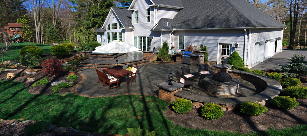 На фото: большой солнечный участок и сад на заднем дворе в классическом стиле с местом для костра, хорошей освещенностью и мощением тротуарной плиткой