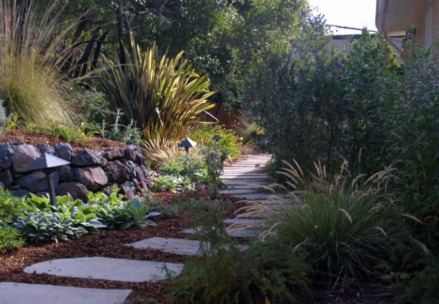 Exemple d'un grand jardin arrière méditerranéen au printemps avec une exposition partiellement ombragée et des pavés en pierre naturelle.