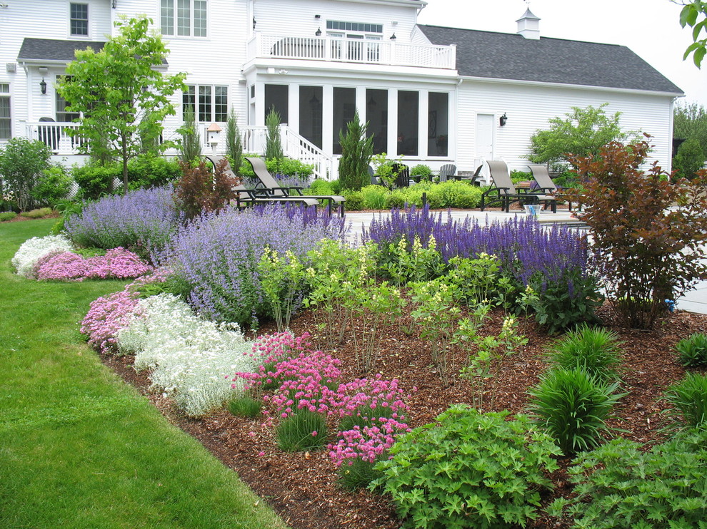 Geometrischer Klassischer Garten hinter dem Haus mit Natursteinplatten, direkter Sonneneinstrahlung und Blumenbeet in Burlington